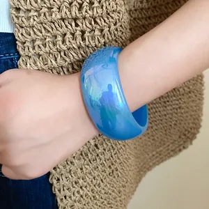 Gros plan d'un bracelet en résine bleue translucide au poignet avec fond en paille