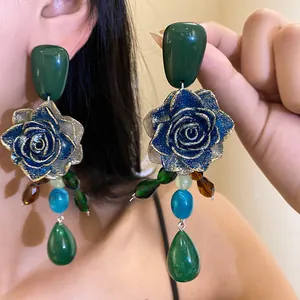 Detailed view of vintage resin rose earrings with emerald green teardrop pendants