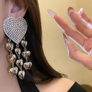 Close-up of shiny rhinestone encrusted heart earrings with metallic charms.