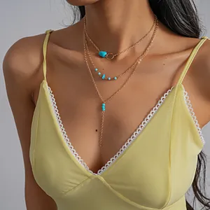 Close-up detail of retro layered gold-tone necklace with turquoise stone accents on model