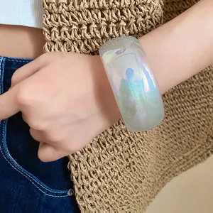 Gros plan détaillé d'un large bracelet jonc en résine irisée au poignet pour le style d'été