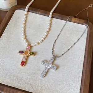Close-up of pearl and silver chain necklaces with sparkling gemstone cross pendants