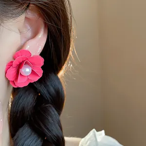 Close-up of vibrant fuchsia flower earrings with a pearl center on a model
