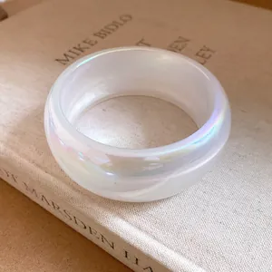 Détail d'un bracelet large en résine blanche translucide avec des reflets irisés