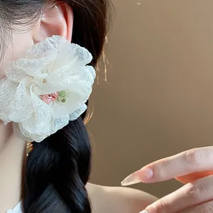 Close-up detail of white chiffon flower statement earrings worn by an elegant model