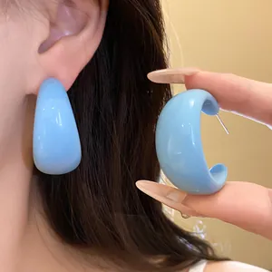Détail en gros plan de boucles d'oreilles en résine bleu clair en forme de C portées