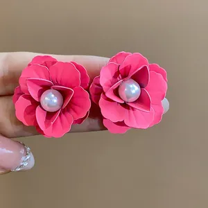 Macro detail of vibrant pink spray-painted flower earrings with elegant central pearls.