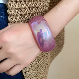 Gros plan d'un large bracelet en résine gelée violette au fini irisé sur le poignet