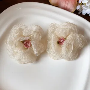 Macro detail of elegant cream chiffon flower stud earrings with mini pink rose center.