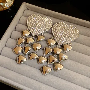 Detailed view of silver heart tassel earrings with sparkling rhinestones in a gray tray.