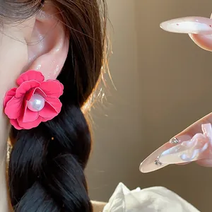 Detailed macro view of a vibrant red flower earring with pearl center worn on ear