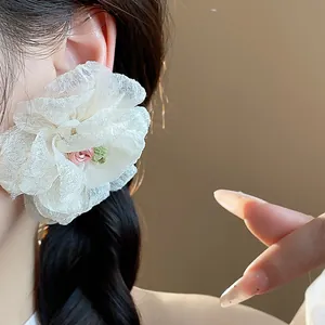 Close-up of elegant white chiffon flower stud earring with delicate pink rose center