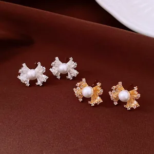 Macro view of gold and silver fan-shaped pearl stud earrings with zircon stones