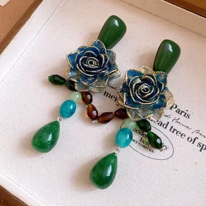 Close-up of vintage style blue resin rose earrings featuring colorful crystal drop pendants