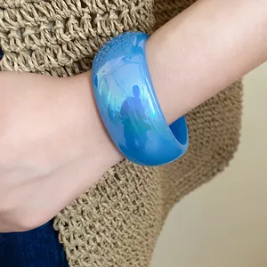 Vue détaillée d'un bracelet jonc en résine bleu gelée translucide large sur un poignet