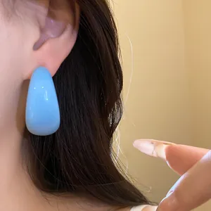 Gros plan d'une boucle d'oreille en résine bleue avec une surface lisse et brillante