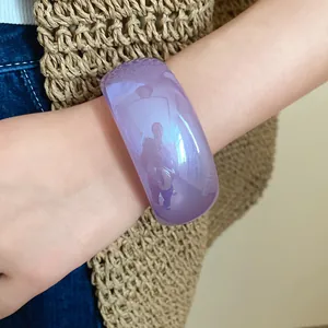 Gros plan d'un large bracelet en résine violette avec une finition gelée translucide au poignet