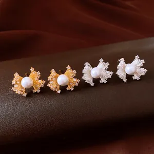 Detailed close-up of vintage zircon and pearl fan-shaped stud earrings in gold and silver tones