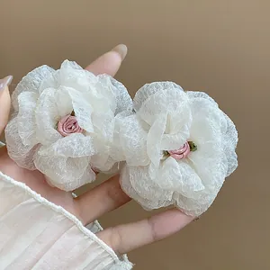 Close-up detail of elegant white chiffon flower stud earrings with pink rose center