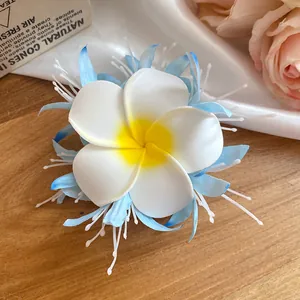 Primo piano di una molletta per capelli a fiori bohémien con petali bianchi e blu