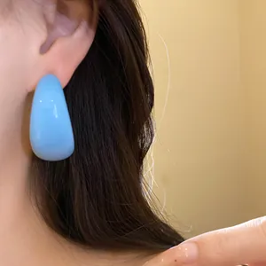 Gros plan d'une boucle d'oreille géométrique en résine bleu clair en forme de C
