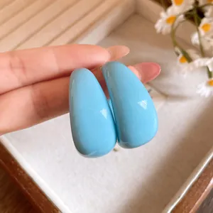 Vue macro montrant la texture lisse de la résine bleu clair de ces boucles d'oreilles en C