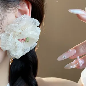 Close-up detail of a delicate white chiffon flower stud earring worn by a model