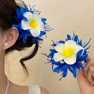 Primo piano di un fermaglio per capelli a fiore di plumeria blu e bianco indossato