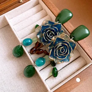 Close-up of vintage resin blue rose earrings with green crystal droplets in box