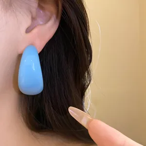 Détail d'une boucle d'oreille minimaliste en résine bleu ciel portée par un mannequin