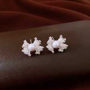 Detailed view of vintage fan-shaped zircon stud earrings with a central elegant pearl