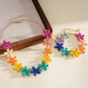 Detailed shot of a colorful raffia flower necklace and bracelet set on a wooden tray