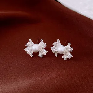 Macro view of vintage fan-shaped silver earrings with central pearl and zirconia details