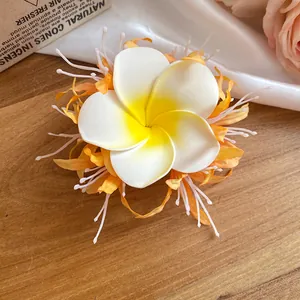 Dettaglio di un fermaglio per capelli a fiori boho con realistici petali di frangipane.