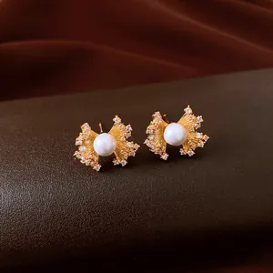 Detailed view of vintage gold fan-shaped pearl earrings with elegant zircon crystals