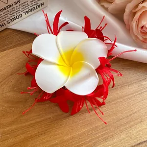 Dettaglio del fermaglio per capelli a fiore di frangipani in tessuto rosso e bianco
