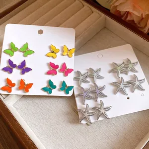 Detalle del juego de pendientes de mariposa y estrella de mar de esmalte en caja de joyas
