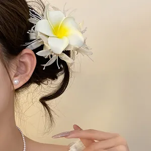 Primo piano di un fermaglio per capelli a fiore di frangipane bohémien indossato da una modella