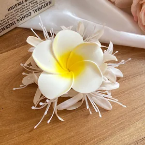 Primo piano di un fermaglio per capelli a forma di fiore di frangipani in tessuto bianco