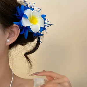 Dettaglio di un fermaglio per capelli a fiore di plumeria blu e bianco in stile bohémien
