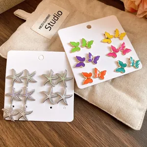 Primer plano de pendientes de mariposa y estrella de mar en tarjetas blancas