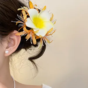 Dettaglio ravvicinato di un fermaglio per capelli a fiore di plumeria in stile bohémien