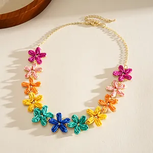 Detail of colorful raffia flower necklace with vibrant woven petals and gold chain.