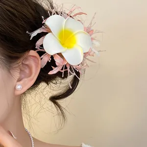 Primo piano di una molletta per capelli a fiore di plumeria in stile boho sui capelli.