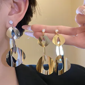 Detail of minimalist geometric polished tassel earrings with zircon shown on ear