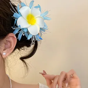 Dettaglio di un fermaglio per capelli a fiore in tessuto boho blu e bianco sul lato