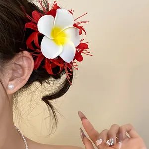 Dettaglio del fermaglio per capelli con giglio ragno rosso e fiori di frangipane sui capelli