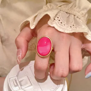 Large oval resin statement ring in vibrant hot pink with a matte gold minimalist bezel frame