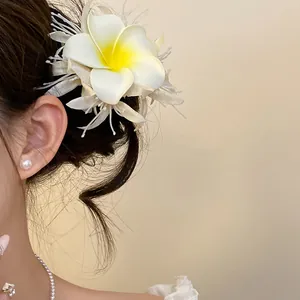 Dettaglio di un fermaglio per capelli a fiore di plumeria in tessuto bianco su modella