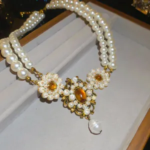 Detail view of a vintage multi-layer pearl necklace with an ornate golden pendant.